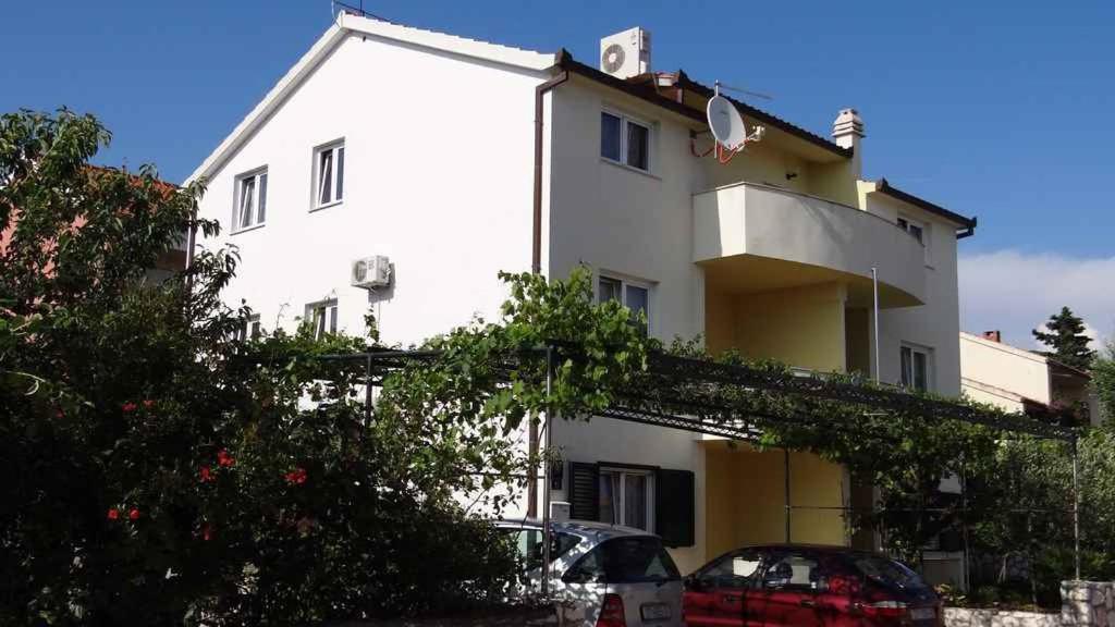 a white building with cars parked in front of it at Apartment Okrug Gornji 32 in Trogir
