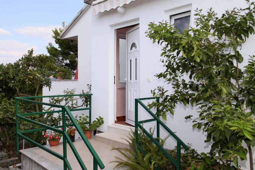 ein weißes Haus mit einem grünen Geländer neben einer Tür in der Unterkunft Apartment Okrug Donji 6 in Okrug Gornji