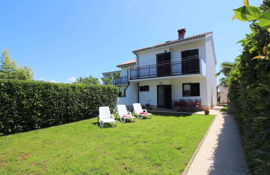 un groupe de chaises assises sur une pelouse devant une maison dans l'établissement Holiday home in Porec/Istrien 10231, à Poreč