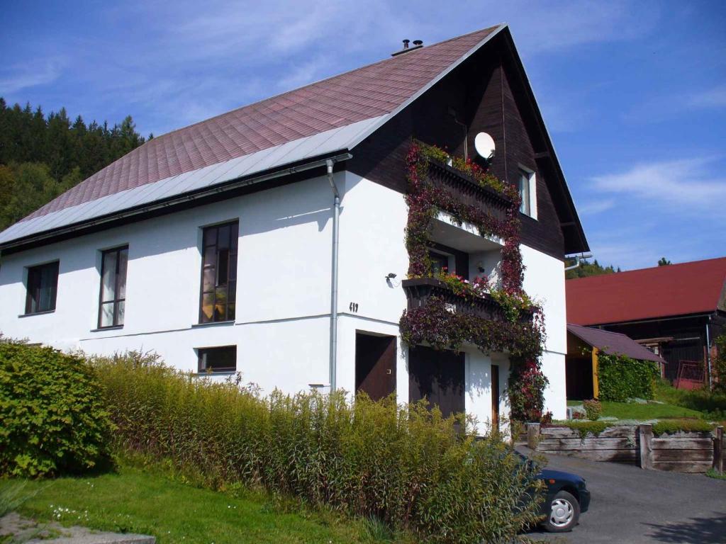 een wit huis met een rood dak en bloemen erop bij Apartment in Rokytnice nad Jizerou 2471 in Rokytnice nad Jizerou