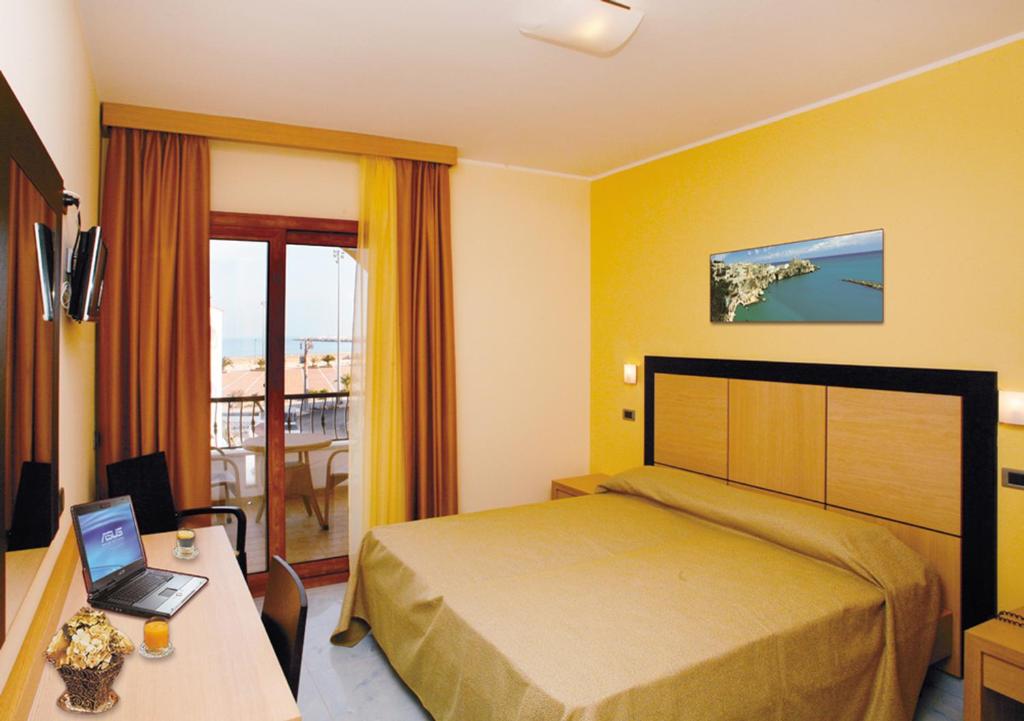 ヴィエステにあるMarc Hotelのベッド、デスク、ノートパソコンが備わるホテルルームです。