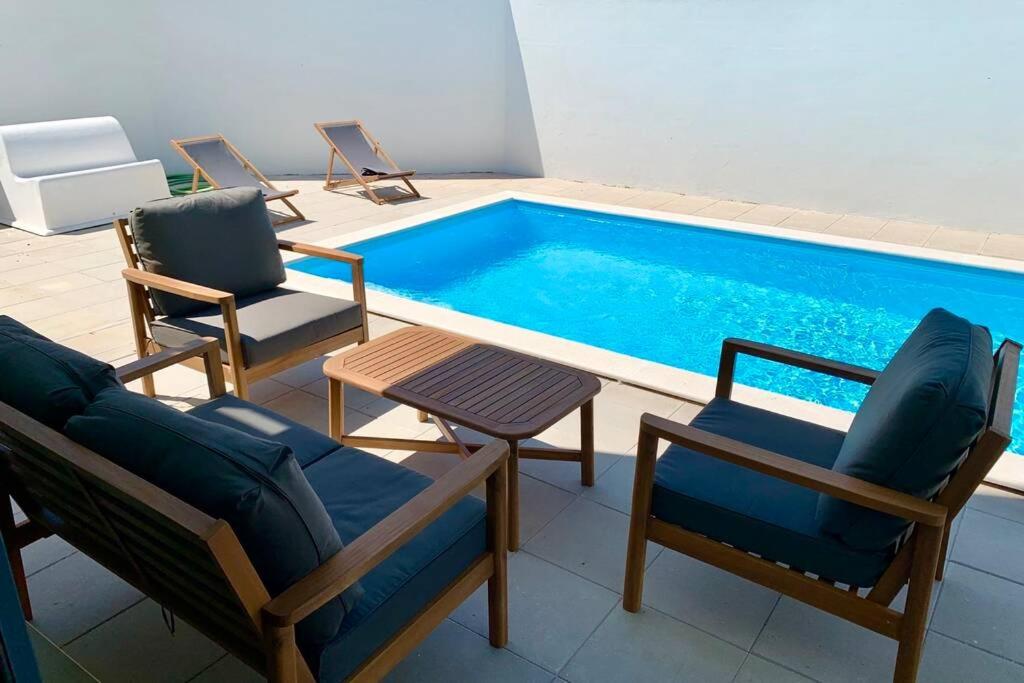 un gruppo di sedie e una piscina di New and modern 3 bedroom Villa with private heated pool near Nazaré a São Martinho do Porto