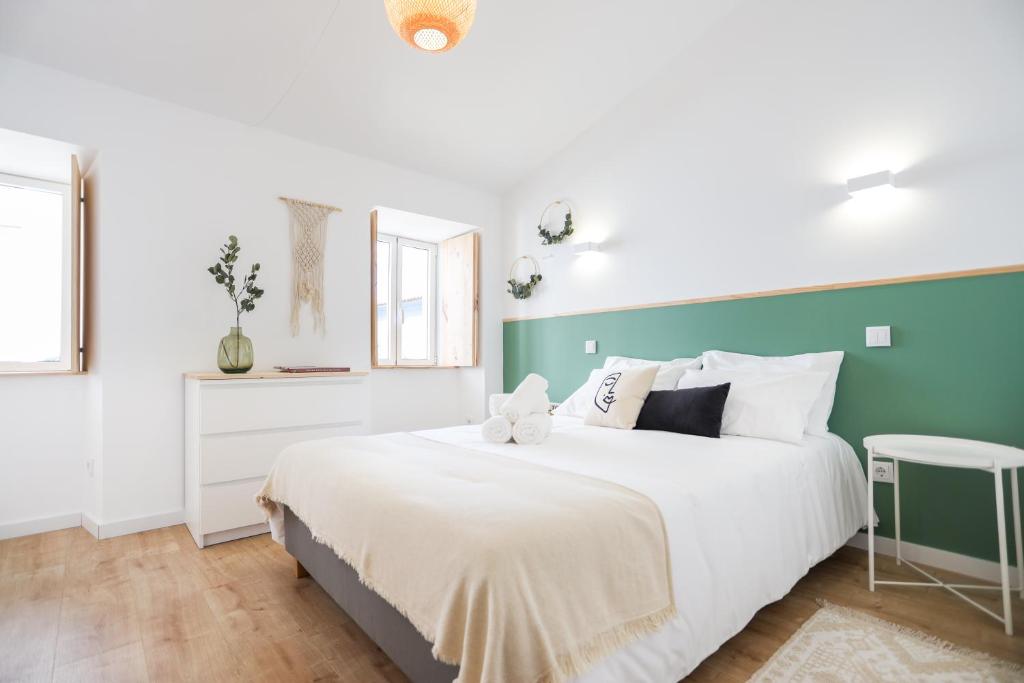 a bedroom with a white bed and a green wall at Casa da Praça in Bragança