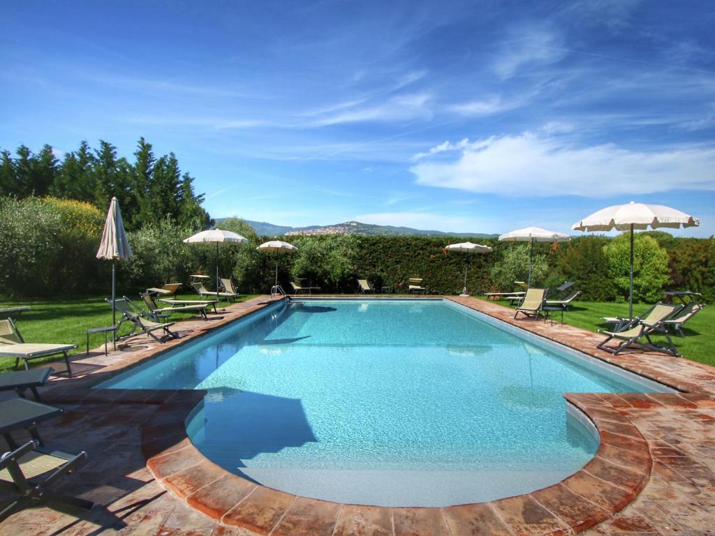 a swimming pool with chairs and umbrellas at Belvilla by OYO Grano in Cortona