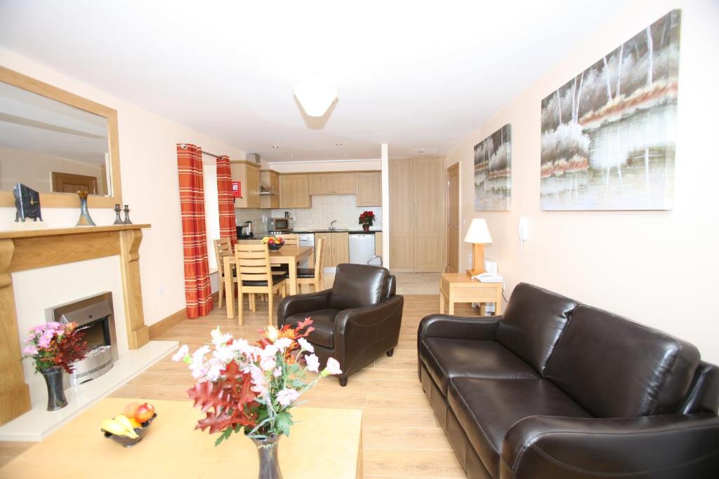 sala de estar con muebles de cuero negro y chimenea en St Angela's Lakeside Aparthotel SALA, en Sligo