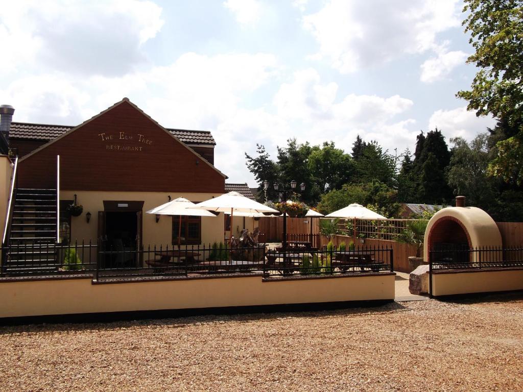 a restaurant with tables and umbrellas in front of a building at The Elm Tree Inn in Wisbech