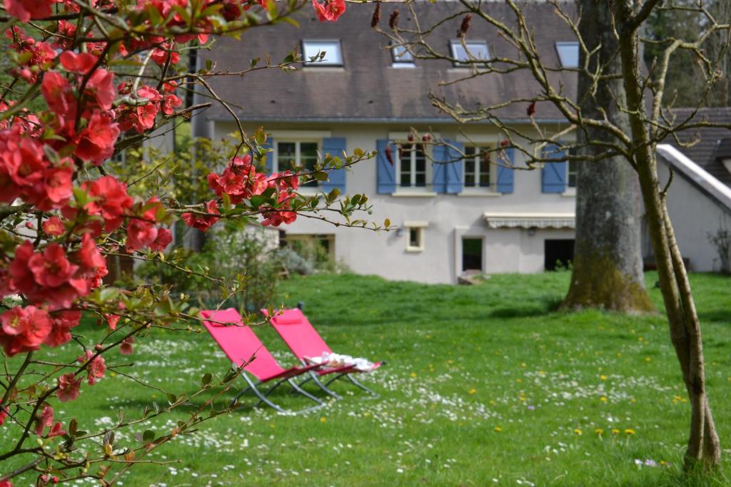 uma cadeira rosa sentada na relva em frente a uma casa em Chambres d'hôtes Villa de Vienne-en-Arthies em Vienne-en-Arthies