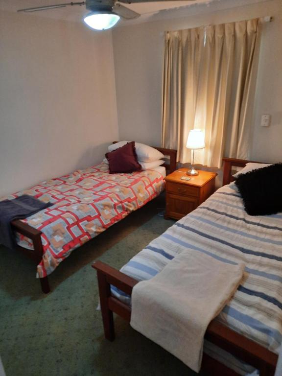 a bedroom with two beds and a table with a lamp at Comfortable Secure Homeshare in Perth