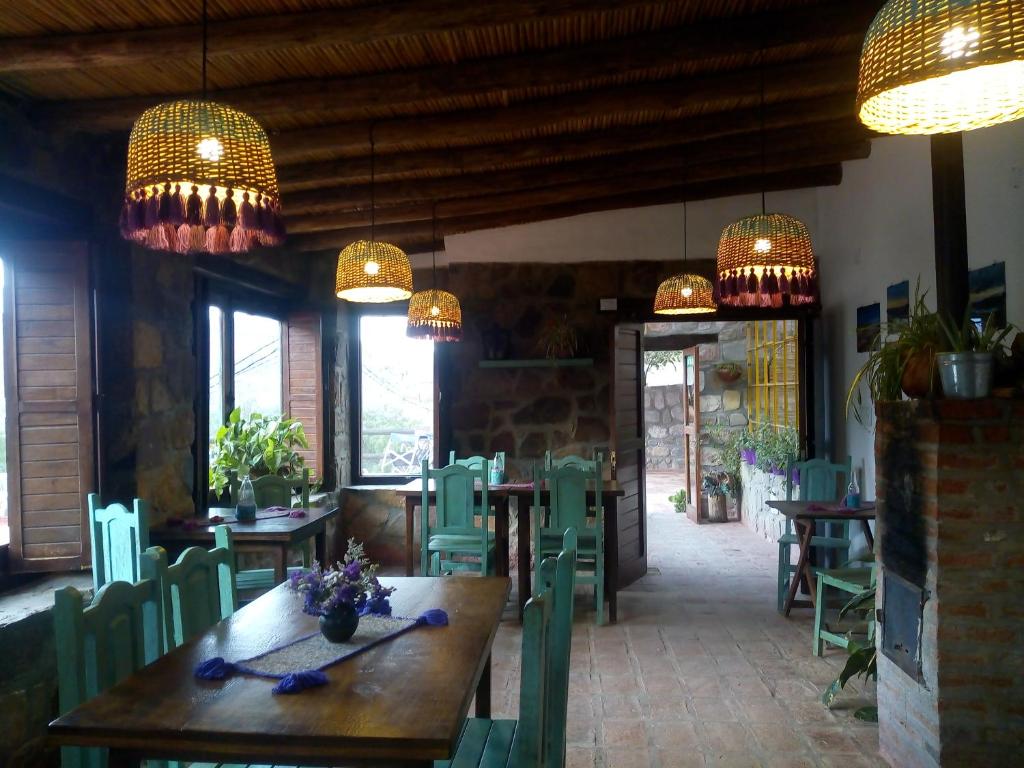 un restaurant avec une table en bois, des chaises et des lustres dans l'établissement Hostal de Altura, à Tilcara