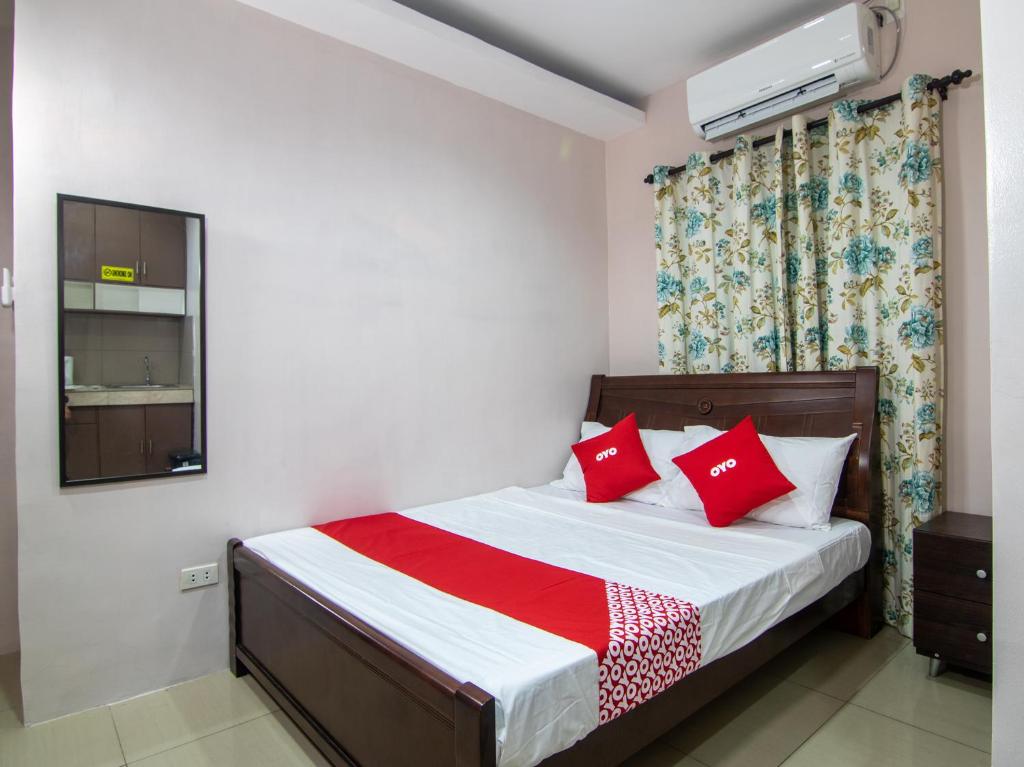 1 dormitorio con 1 cama con almohadas rojas en OYO 766 Ichehan Apartments, en Manila