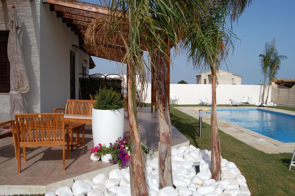 a patio with a table and palm trees and a pool at Villa Al Mare Guest House in Tre Fontane