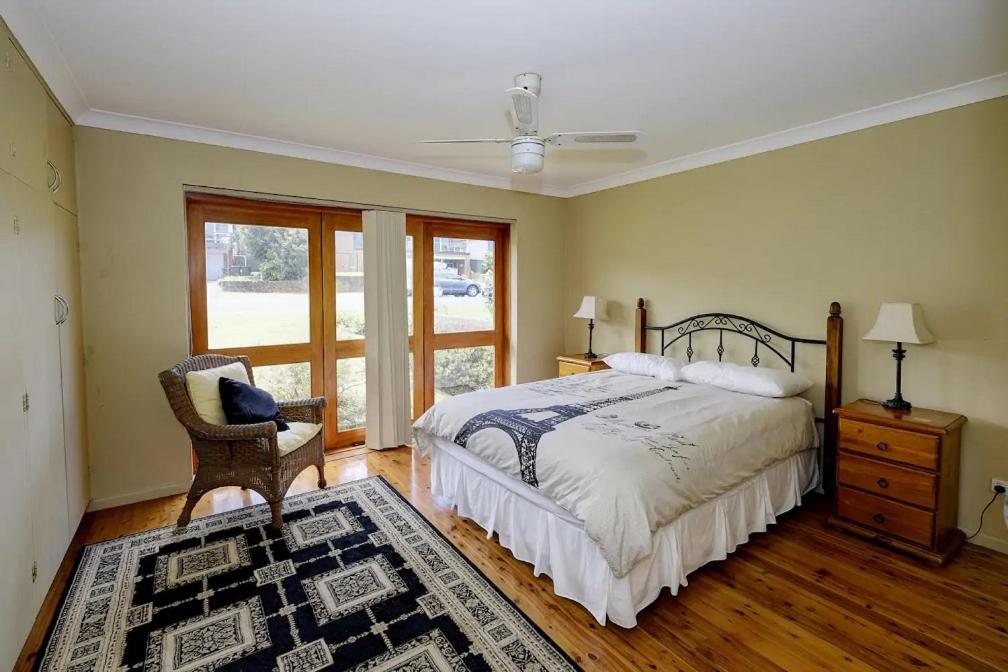 Un dormitorio con una cama y una silla y una ventana. en Retreat on Gleeson, en Forster