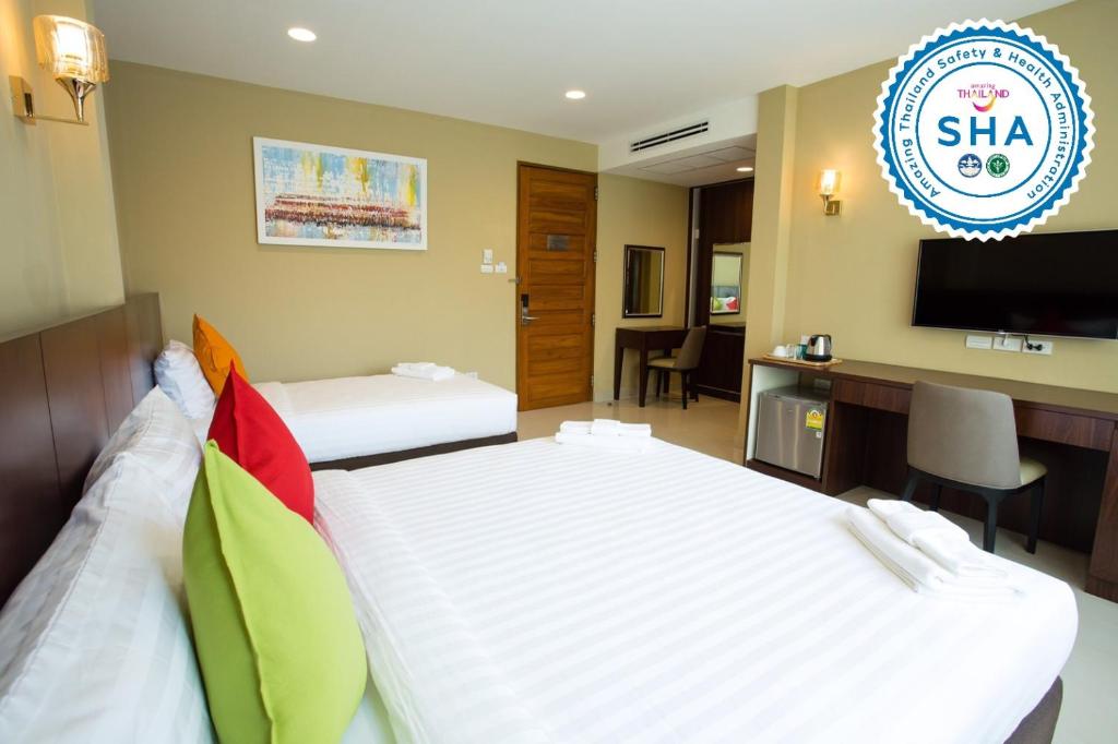 A twin room with a wall-mounted television, desk, mini-fridge and two beds.