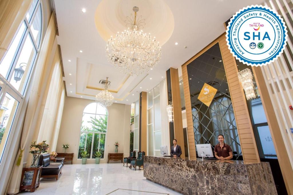 A tall, chandelier-lit lobby places the reception desk beneath a bright, formal entrance hall.