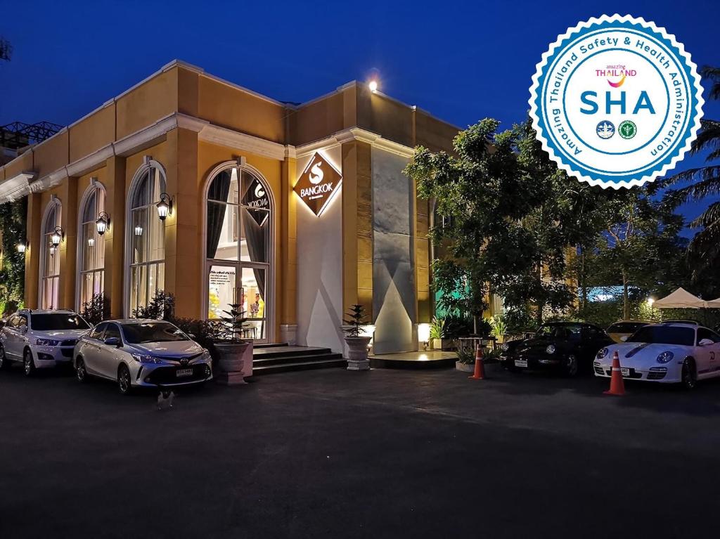 a building with cars parked in a parking lot at S Bangkok Hotel, Navamin in Ban Khi Sua