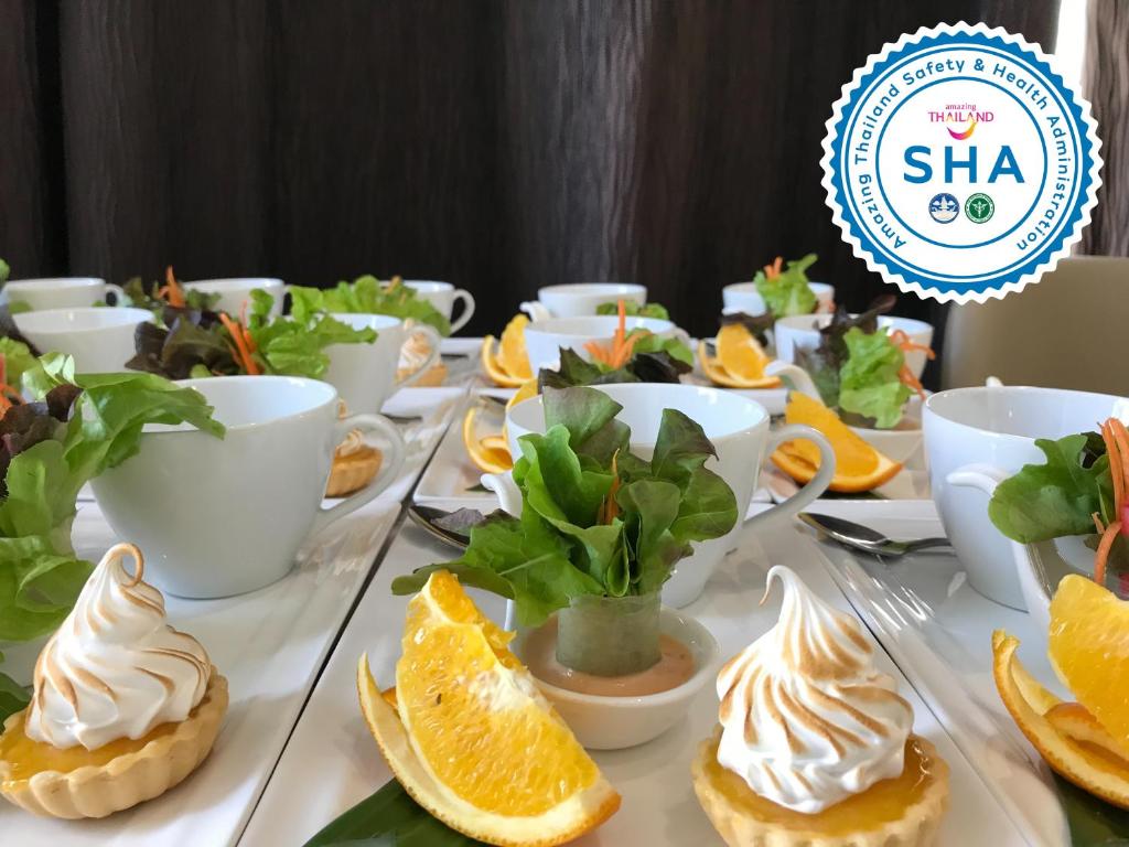 A dessert display with small meringue tarts, oranges, greens and tableware.