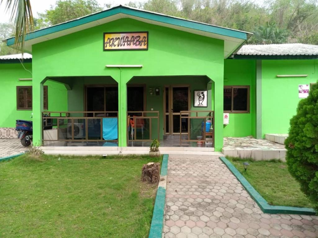 ein grünes Gebäude mit einem Schild davor in der Unterkunft PANAASA GUEST HOUSE in Akosombo