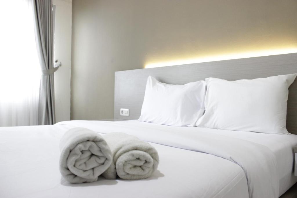 a bedroom with a white bed with towels on it at Stylish Studio Apartment at Harvard Jatinangor near ITB By Travelio in Sayang