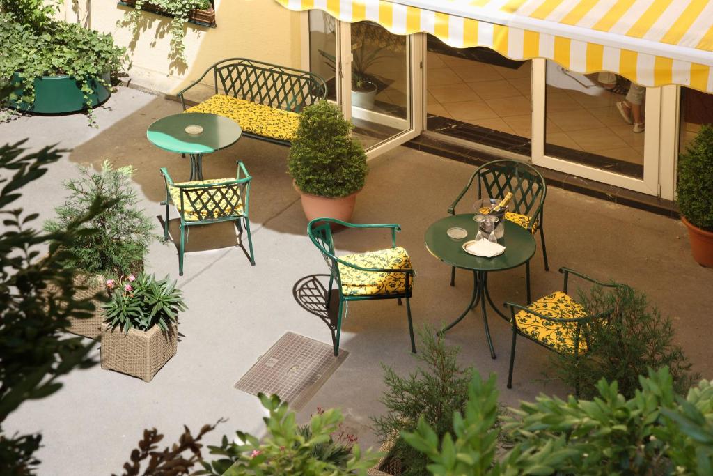an outdoor patio with chairs and tables and plants at Hotel Secession an der Oper in Vienna