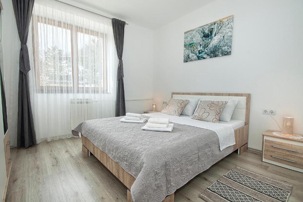 a white bedroom with a large bed and a window at Apartman Lujko Plitvice in Plitvička Jezera