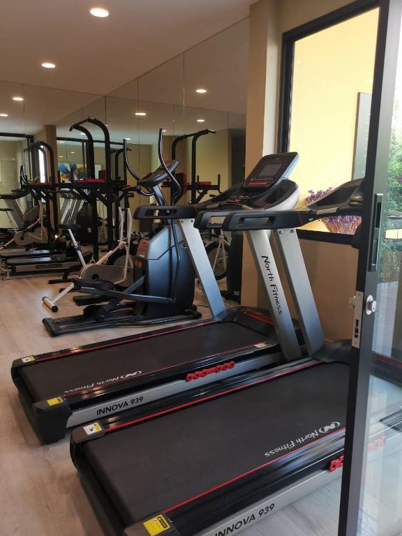 The fitness room is equipped mainly with treadmills and elliptical-style cardio machines beside a window.