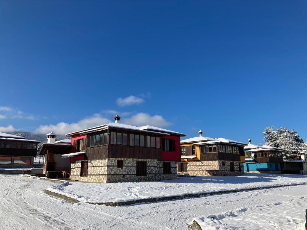 a row of houses with snow on the ground at Вилно селище Баташки хан in Tsigov Chark
