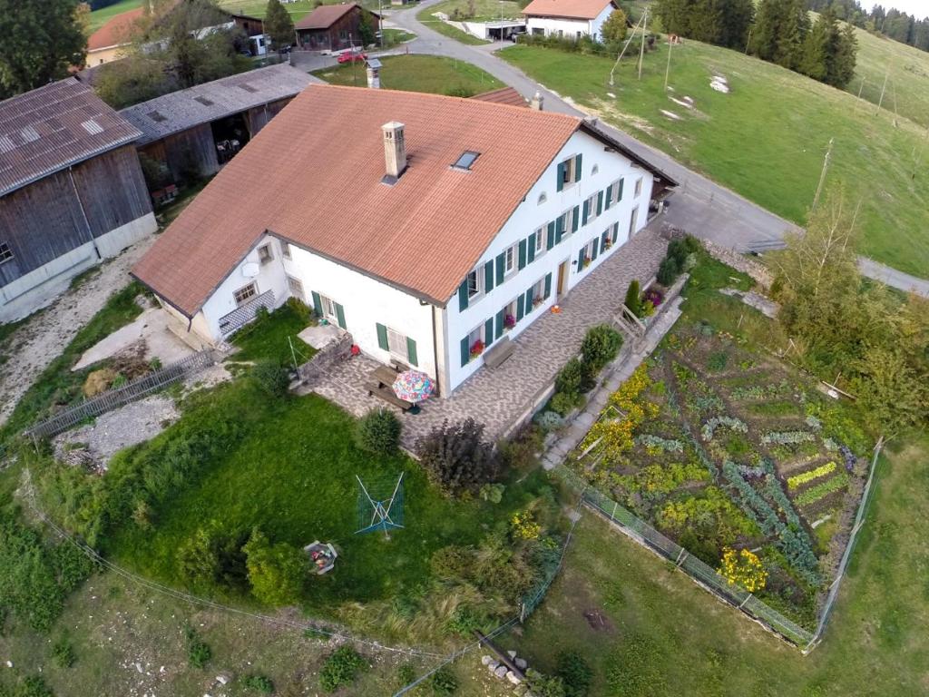 an aerial view of a white house with a roof at Ferme O'Clés in Le Peuchapatte