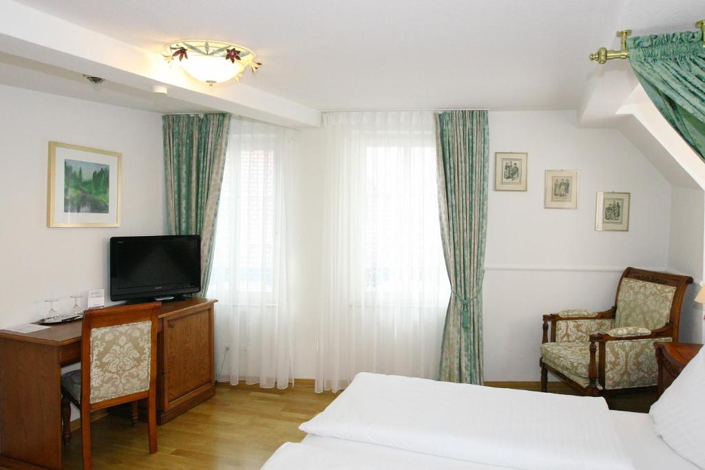 a bedroom with a bed and a desk and a television at Hotel Rathausglöckel in Baden-Baden