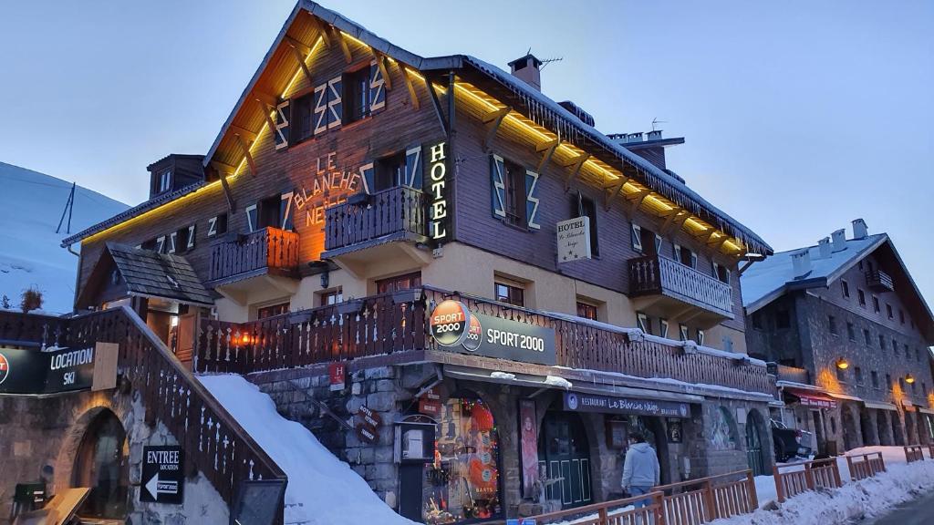 a building on a street with snow on the ground at Hotel Le Blanche Neige in Valberg