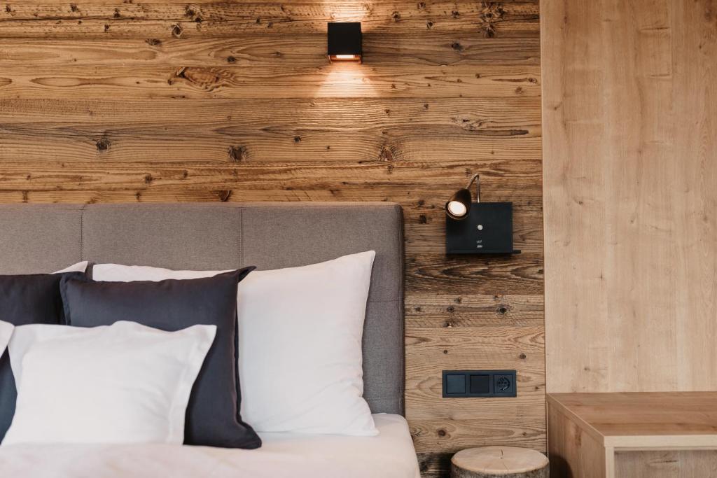 a bedroom with a bed with a wooden wall at Alte Schmiede - das kleine Hotel in Wagrain