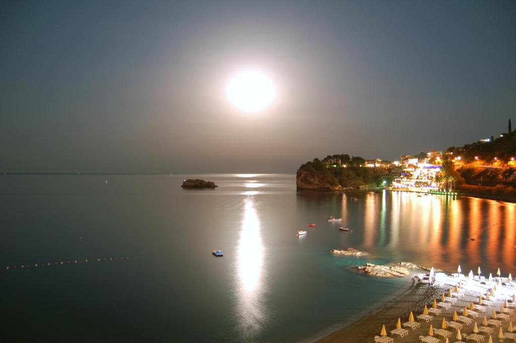 a view of a body of water at night with the moon at Hotel Lido Mediterranee in Taormina