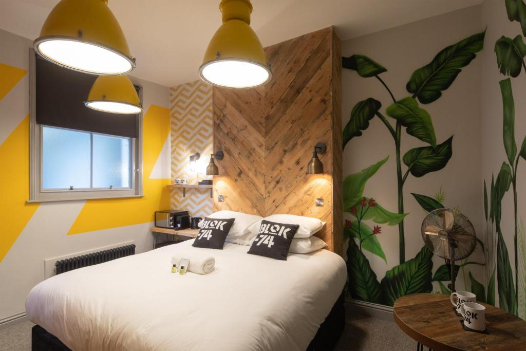a bedroom with a large white bed with plants on the wall at Blok-74 in Brighton & Hove