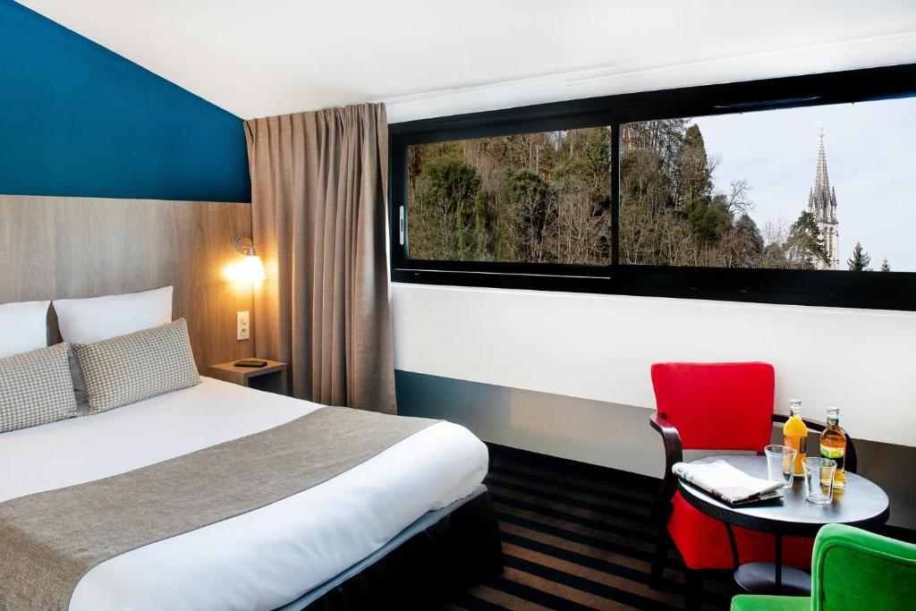 a hotel room with a bed and a window at Hôtel Panorama in Lourdes