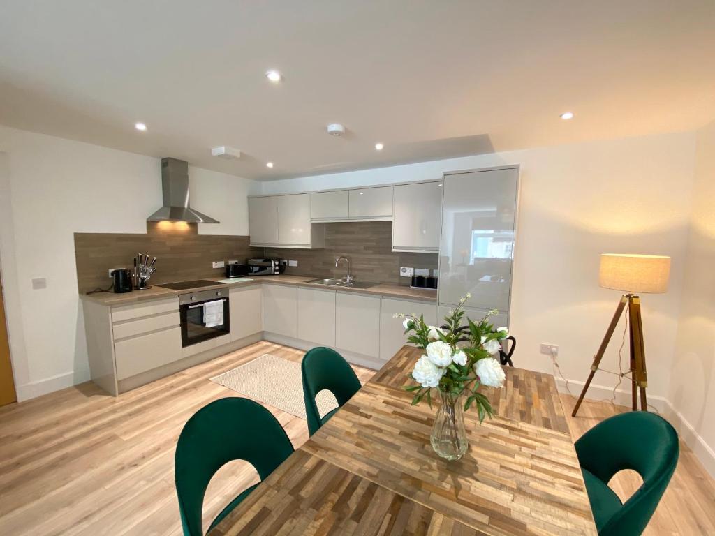 a kitchen with a wooden table and green chairs at High Street, Stylish City Centre Apartment, 3 Bed in Perth