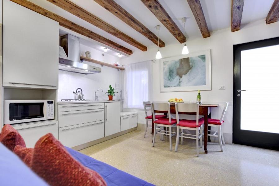 a kitchen with a table and chairs in a kitchen at Cozy Apartment up to 4 in Biennale Giardini by Bricola Apartments in Venice
