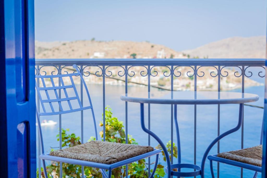 two chairs on a balcony with a view of the water at Marea Apartments in Symi