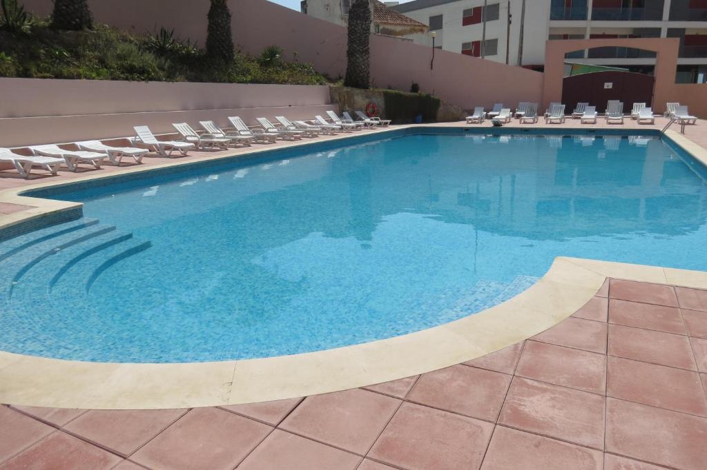 una gran piscina con sillas y un edificio en Olá Ericeira Apartment, en Ericeira