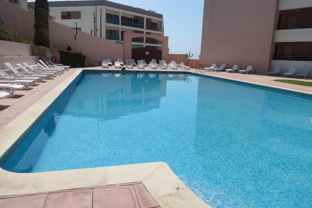 Una gran piscina con sillas y un edificio. en Olá Ericeira Apartment, en Ericeira