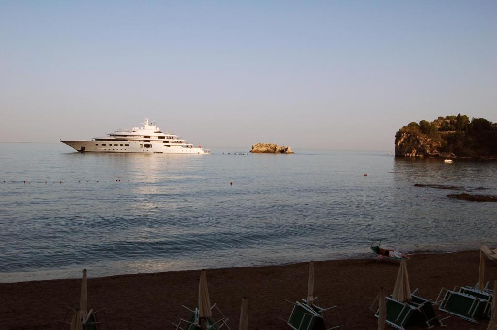 a cruise ship in the water with a beach at Hotel Lido Mediterranee in Taormina