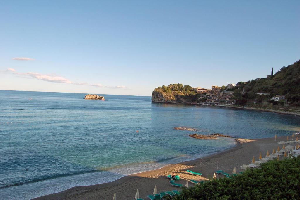 a beach with a bunch of umbrellas and the ocean at Hotel Lido Mediterranee in Taormina