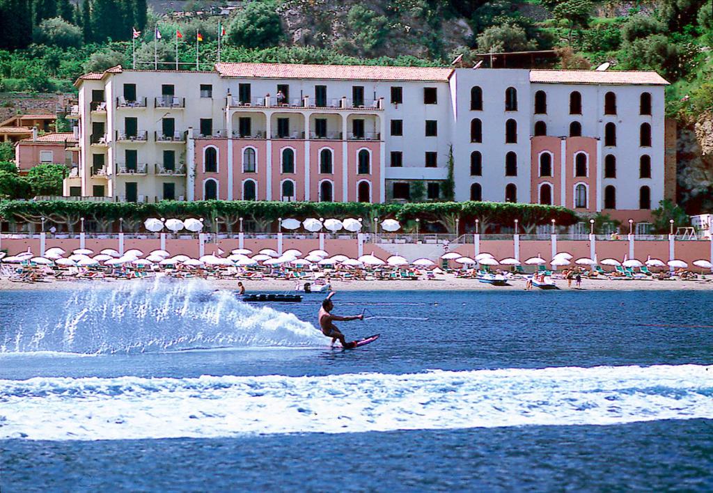 a person on a surfboard in the water at a beach at Hotel Lido Mediterranee in Taormina