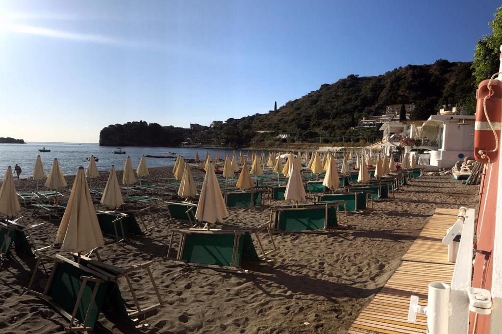 a row of beach chairs and umbrellas on a beach at Hotel Lido Mediterranee in Taormina