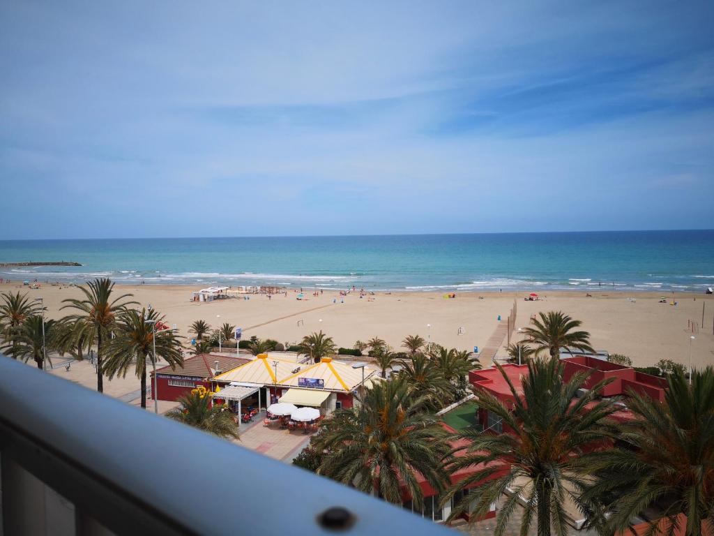 a view of a beach with palm trees and the ocean at 1ere soleil levant in Puerto de Sagunto