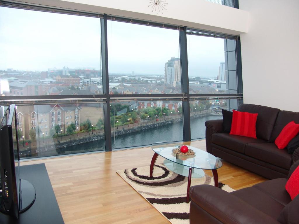 a living room with a couch and a table and large windows at Quay Apartments in Manchester