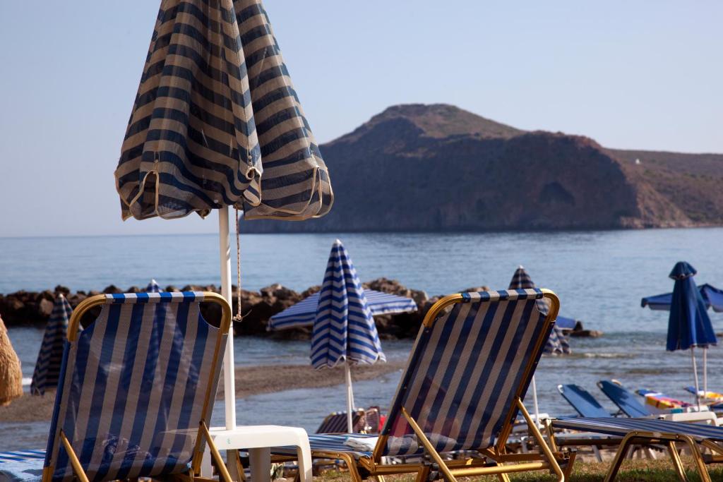 a group of chairs and umbrellas on a beach at Ermis Suites in Platanias