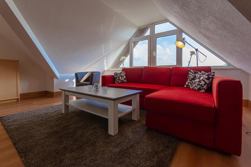 sala de estar con sofá rojo y mesa en Ferienwohnung Mohnblume - Strandhaus Lobbe, en Middelhagen