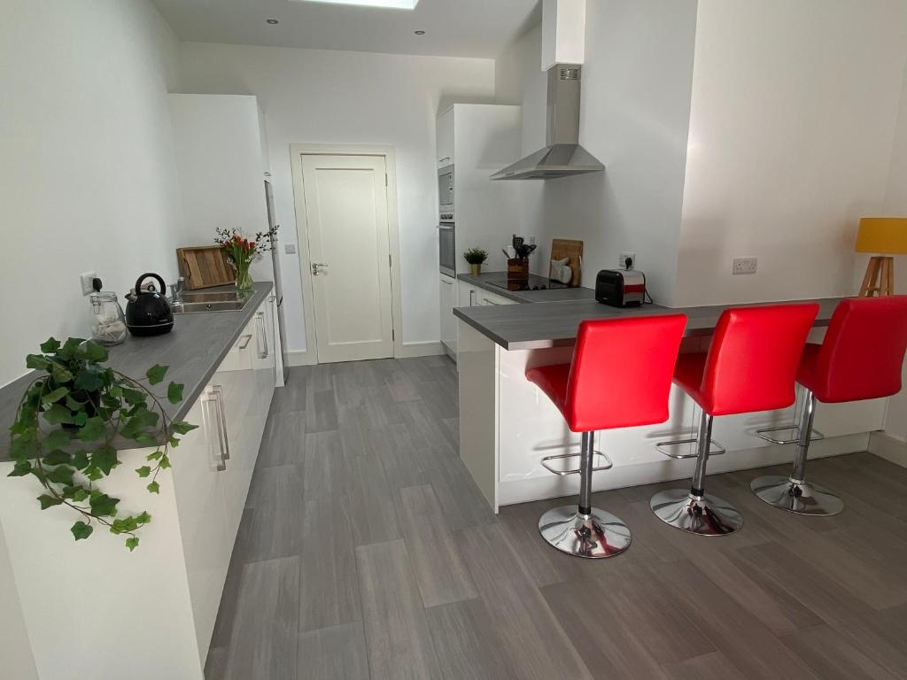 a kitchen with two red chairs and a counter at Apt 4 - Silver Spruce in Killarney