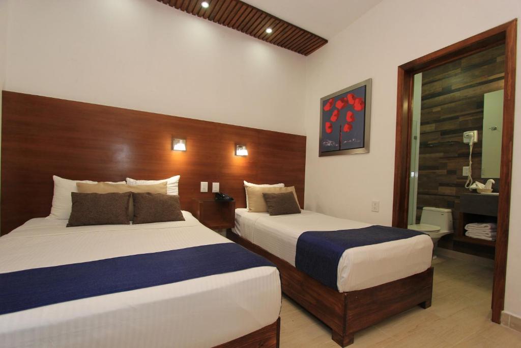 Habitación de hotel con 2 camas y espejo en Hotel del Carmen, en el Centro- DESAYUNO Incluido ! en Tuxtla Gutiérrez