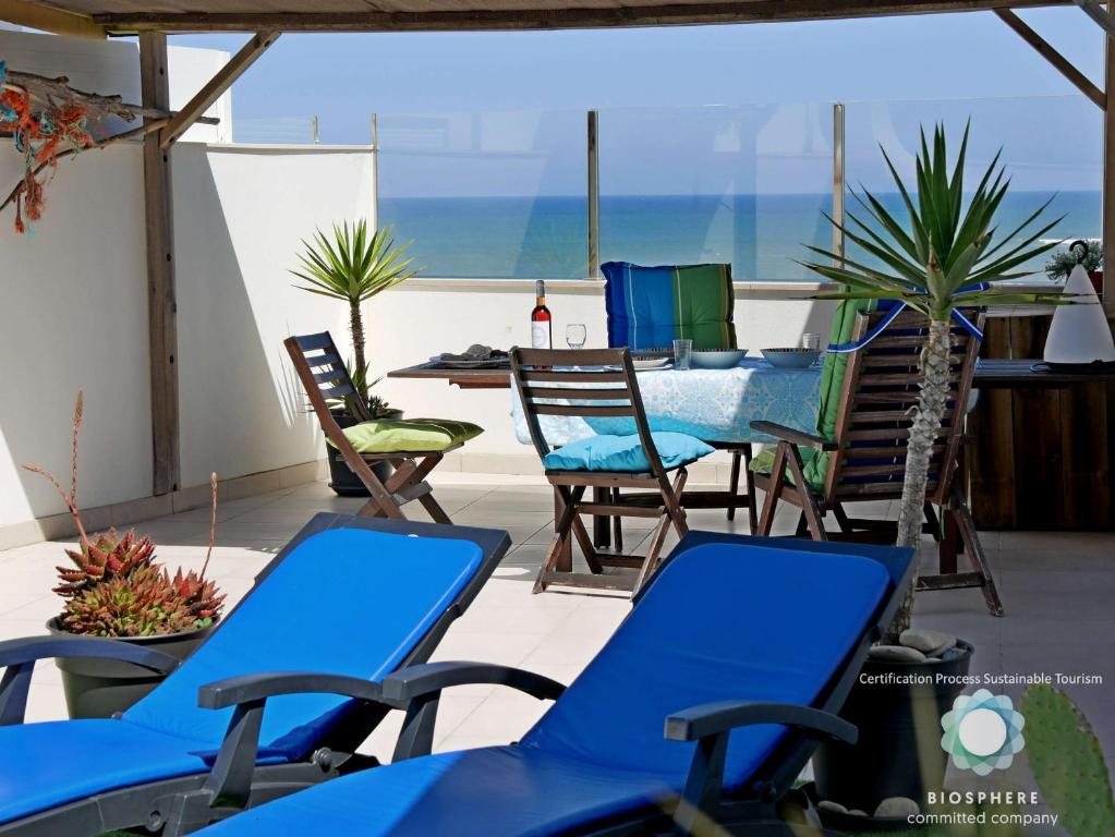 パタイアスにあるApartment at Praia Paredes de Vitória by book yourholiday ptの青い椅子とテーブルが備わるパティオ、海