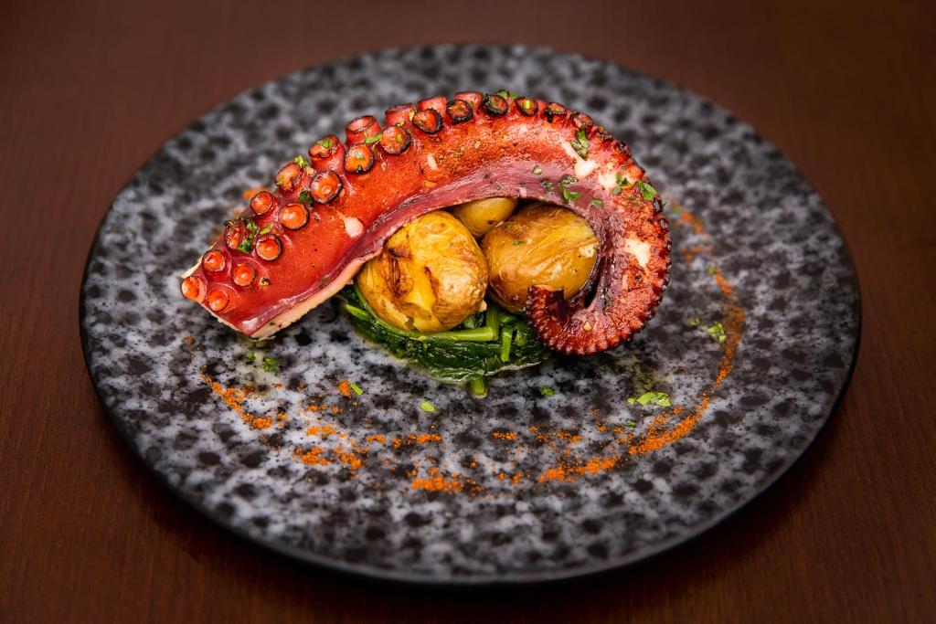 a plate with a sausage and vegetables on a table at Gallery Hostel in Porto